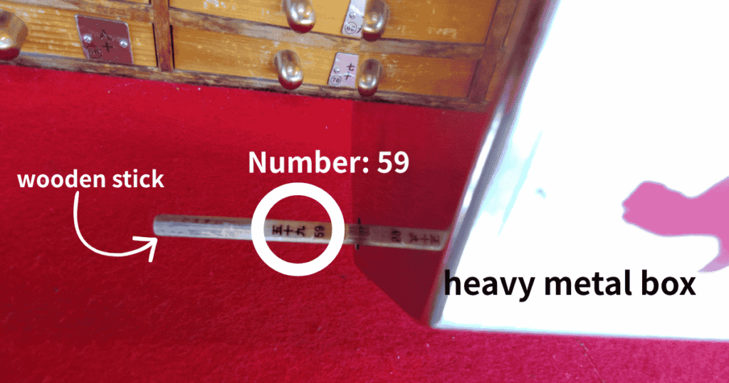 Taking a numbered wooden stick out of a heavy metal box